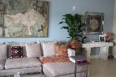 North Miami water front residence remodel project.  Furniture plan, finishes and decorating project.  Owners own art.  In Living Room modern linen sofa with attached chaise.  Neutral color palette on walls and floor (sand and sky) with bright orange accents. 