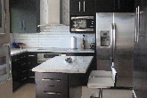 Kitchen custom ebonized rift cut oak cabinetry with Kashmir White granite and white ceramic subway tile.